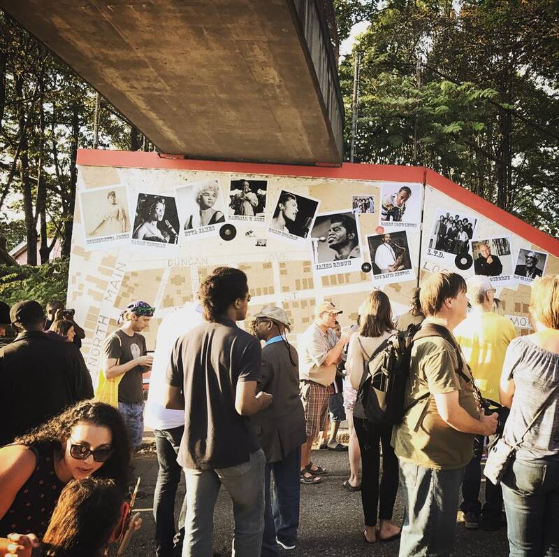 Large crowd gathered in front of the Mt. Hope Music Mural dedication ceremony under overpass.