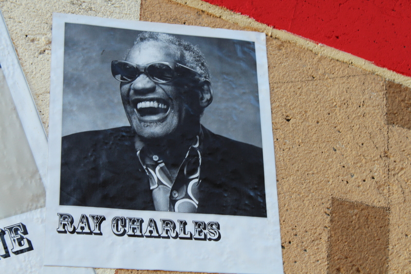 Black-and-white photo of Ray Charles laughing, wearing sunglasses, displayed on the music mural.
