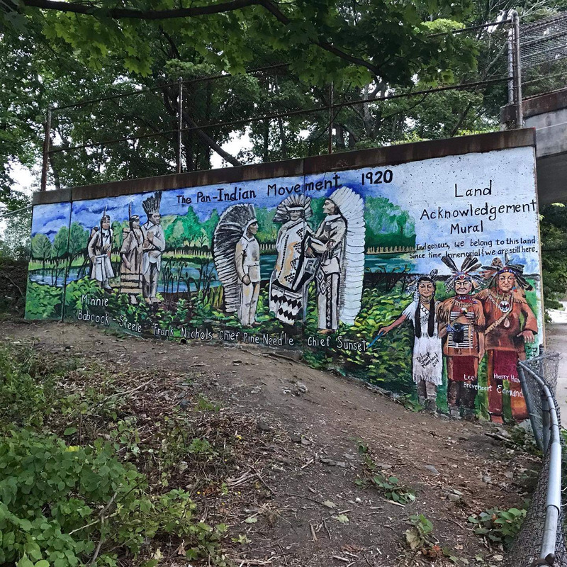 Full view of Land Acknowledgement Mural showing the Pan-Indian Movement 1920 with named Indigenous figures painted on mural wall.