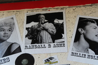 Black-and-white photograph of Randall B. Ashe playing saxophone, flanked by photos of Etta James and Billie Holiday.