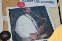Mural photo of Rev David Hector holding a saxophone, with vinyl records displayed nearby.