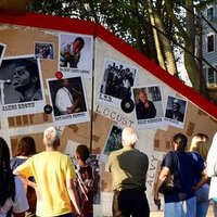 Small crowd viewing the Mt. Hope Music Mural, featuring photos of musicians on a neighborhood map background.