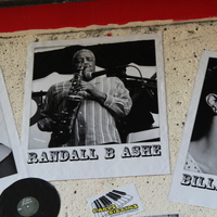 Black-and-white photograph of Randall B. Ashe playing saxophone, flanked by photos of Etta James and Billie Holiday.