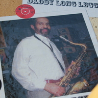 Mural photo of Rev David Hector holding a saxophone, with vinyl records displayed nearby.